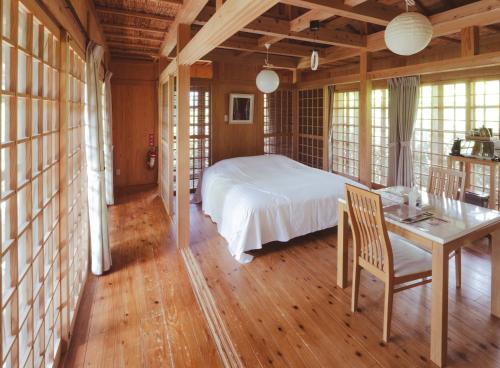 Schlafzimmer mit einem Bett, einem Tisch und Stühlen in der Unterkunft かたあきの里 in Miyako-jima