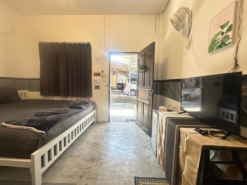 a bedroom with a bed and a television and a door at Walking street hostel & homestay at Haadrin in Haad Rin