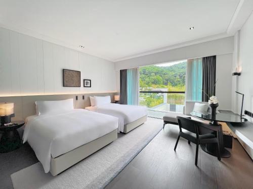 a hotel room with two beds and a desk and a window at Oriental Resort Guangzhou in Guangzhou