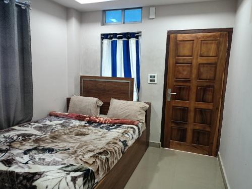 a bedroom with a bed and a wooden door at Hilsan Hotel in Bomdila