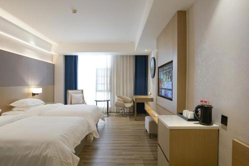 a hotel room with two beds and a desk at Paco Hotel Guangzhou North Railway Station in Huadu