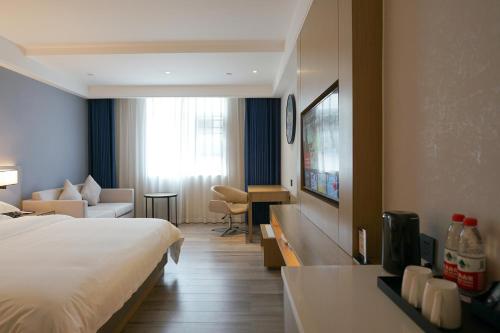 a hotel room with a bed and a living room at Paco Hotel Guangzhou North Railway Station in Huadu
