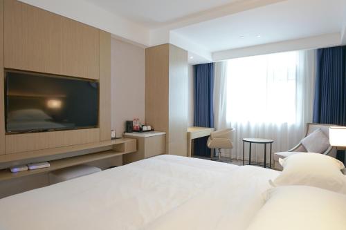 a hotel room with a bed and a flat screen tv at Paco Hotel Guangzhou North Railway Station in Huadu