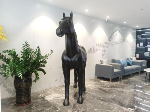 a black horse statue in a room with a couch at Paco Hotel Guangzhou North Railway Station in Huadu
