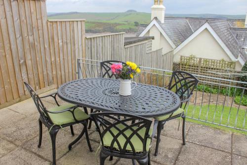 a black table with chairs and a vase of flowers at Waders in Salcombe