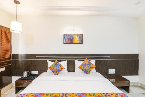a bedroom with a large white bed with colorful pillows at FabHotel Shirdi Park Inn in Shirdi
