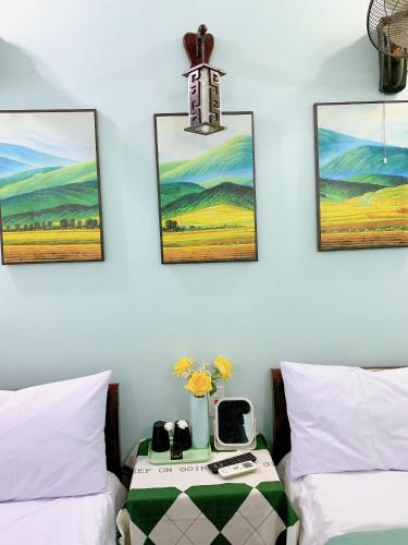 a bedroom with two beds and a table with a clock at Long Guest House in Cat Ba