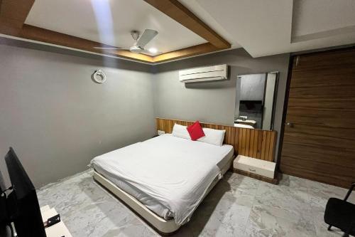 a bedroom with a white bed with a red pillow at Hotel Om Balaji in Ahmedabad