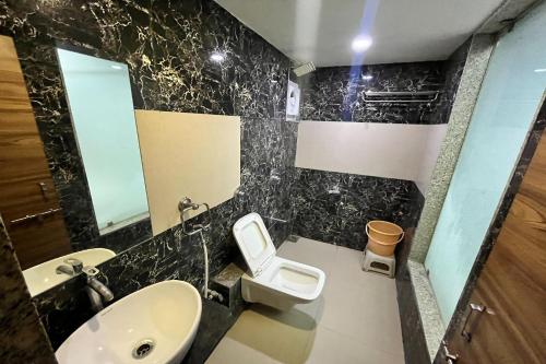 a bathroom with a sink and a toilet and a mirror at Hotel Om Balaji in Ahmedabad