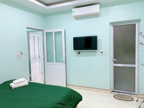 - une chambre avec un lit vert et une télévision dans l'établissement Bao Long Guest House, à Cat Ba