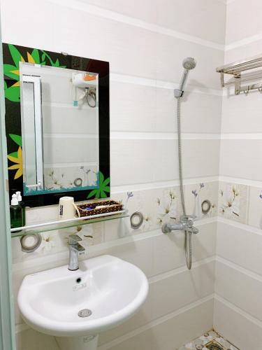 a white bathroom with a sink and a mirror at Long Guest House in Cat Ba