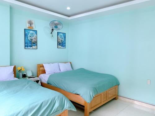 two beds in a room with blue walls at Long Guest House in Cat Ba