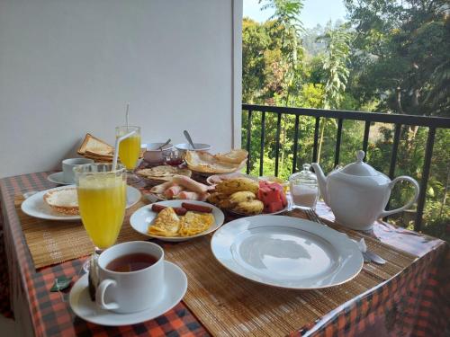 una mesa con desayuno y bebidas en el balcón en Forest Rawana homestay Ella, en Ella