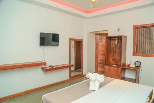 a bedroom with a bed and a tv on the wall at Mount End Hotel Nuwara Eliya in Nuwara Eliya