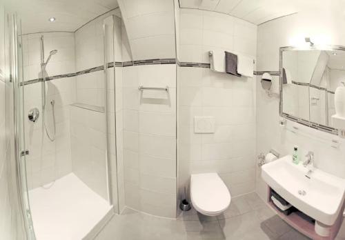a bathroom with a shower and a toilet and a sink at Gästehaus Christophorus - Edelweiß in Krün