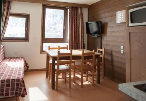 a room with a table and chairs and a tv at Village vacances de Valmeinier "Les Angeliers" in Valmeinier