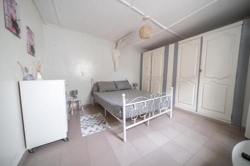 a white bedroom with a bed and a refrigerator at Charmant Studio bien équipé in Dakar