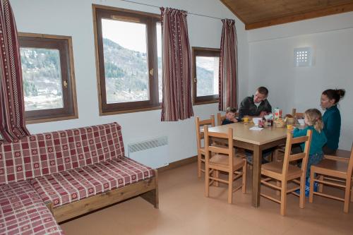 une famille assise à une table dans une pièce dans l'établissement Village vacances de Valmeinier "Les Angeliers", à Valmeinier