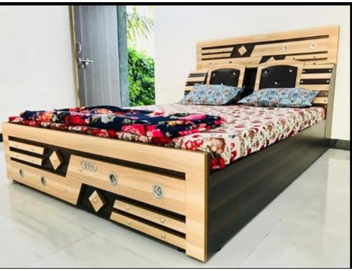 a bedroom with a wooden bed with drawers at Madhuvan Homestay, Junagarh in Sasan Gir