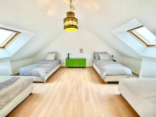 - une chambre mansardée avec 2 lits et une table verte dans l'établissement La Villa Billard - 200 m2 - Jardin, à Saint-Nazaire