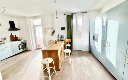 une cuisine avec un comptoir en bois et deux tabourets dans l'établissement La Villa Billard - 200 m2 - Jardin, à Saint-Nazaire