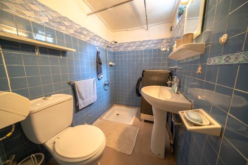 a blue tiled bathroom with a toilet and a sink at Charmant Studio bien équipé in Dakar