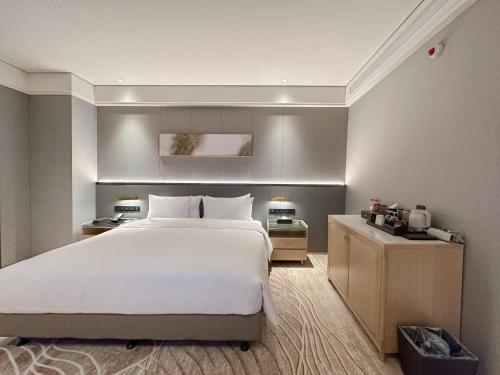 a bedroom with a large white bed and two lamps at Wanda Jin Jiamusi in Jiamusi