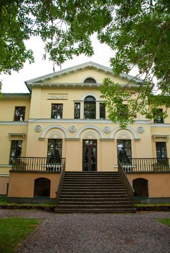 a large building with stairs in front of it at Naukšēnu muiža in Naukšēni