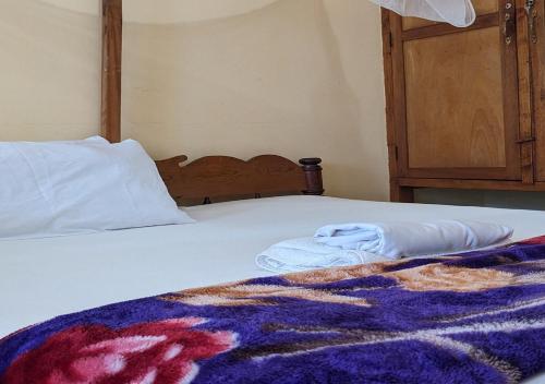a bed with a blanket and two towels on it at Sea Hotel in Pangani
