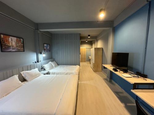 a hotel room with two beds and a television at Bangkok vibe, City House, 7 mins to BTS, City center, Private room in Sathon, Private bathroom, Bangkok, Thailand in Bangkok