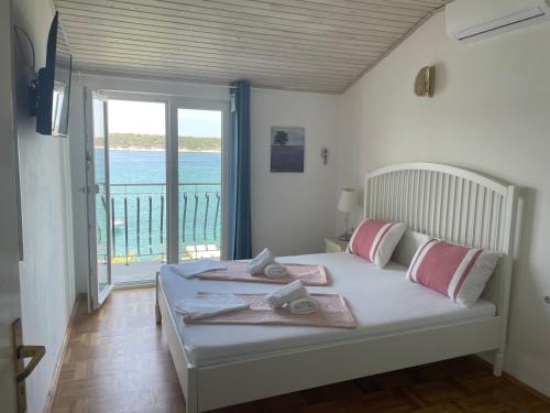 a bedroom with a bed with a view of the ocean at Apartments Vila Miranda in Barbat na Rabu