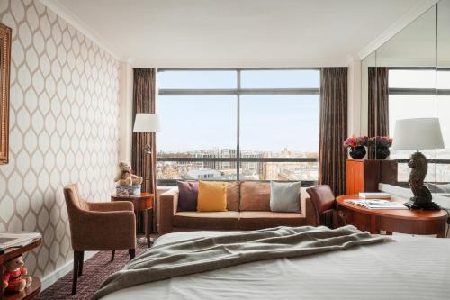 une chambre d'hôtel avec un lit et un salon dans l'établissement Millennium Hotel London Knightsbridge, à Londres