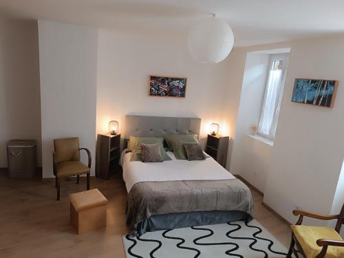 1 dormitorio con 1 cama grande y 2 sillas en Gîte de l'Oustal, en Oust