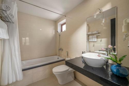 a bathroom with a sink and a toilet and a tub at Bantique Hotel in Da Nang