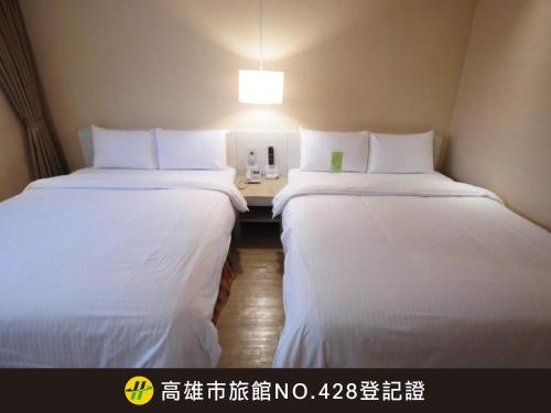 two beds in a hotel room with white sheets at Kindness Hotel - Houyi Jiuru in Kaohsiung