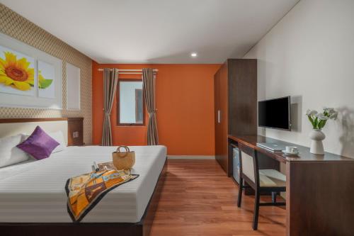 a bedroom with a bed and a desk and a television at Bantique Hotel in Da Nang