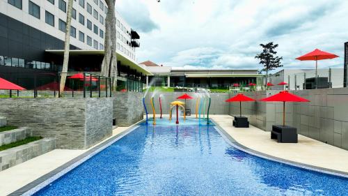 a pool with chairs and umbrellas in a building at Aston Serang Hotel & Convention Center in Serang