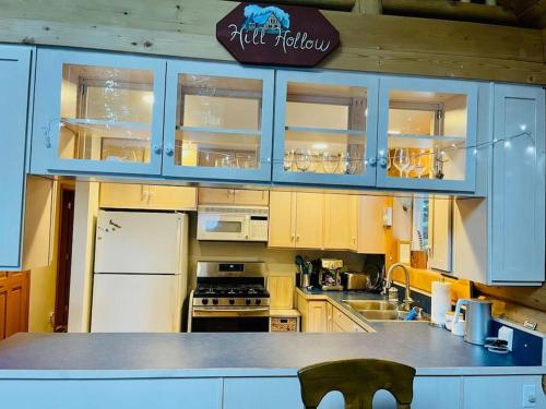 cocina con armarios azules y nevera blanca en Hawthorn Cabin en Pine Glen