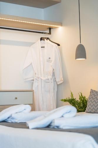 a white robe hanging on a wall next to a bed at Lithos Luxury Suites in Tinos Town
