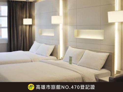 two beds with white pillows in a hotel room at Kindness Hotel - Zhongshan Bade Branch in Kaohsiung