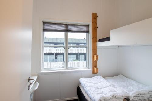 a small bedroom with a bed and a window at Hyggelig sommerhus Øer Maritime ferieby Ebeltoft in Ebeltoft