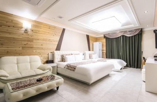 a bedroom with two beds and a couch and a table at Gentleman Hotel in Suncheon