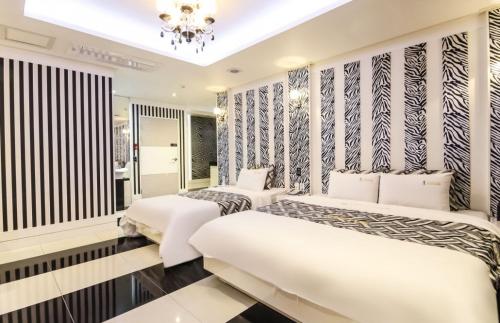 a bedroom with two beds and a chandelier at Gentleman Hotel in Suncheon