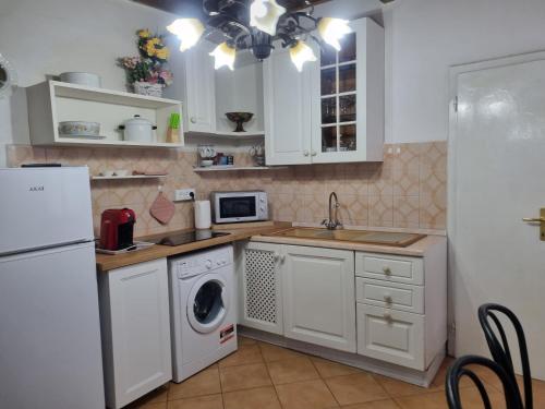 a kitchen with white cabinets and a washer and dryer at Appartamento “Il Borgo” in Peccioli