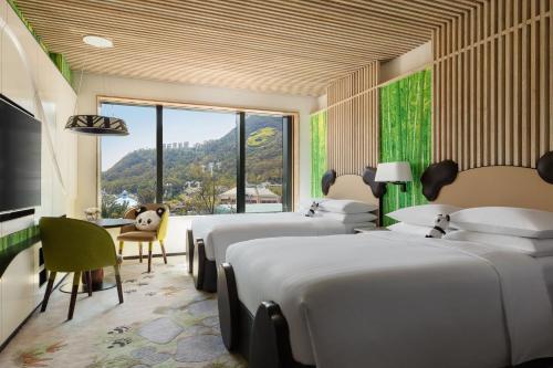 a bedroom with four beds and a desk and a window at Hong Kong Ocean Park Marriott Hotel in Hong Kong
