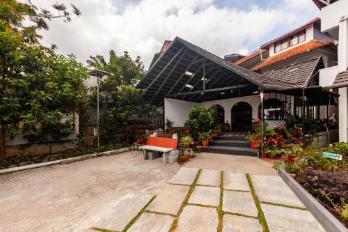 ein Gebäude mit einem Innenhof mit einer Bank und Blumen in der Unterkunft Treebo Trend Vrindavan 3 Km From Madikeri Fort in Madikeri