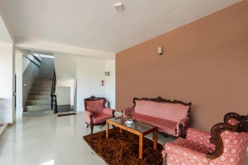Una sala de estar con dos sillas y una mesa. en Treebo Vrindavan, 3 Km From Madikeri Fort, en Madikeri