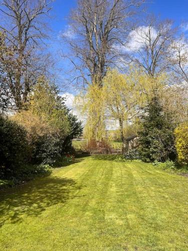 a field of grass with trees in the background at Alba Cottage, Wilcot, Pewsey in Wilcot