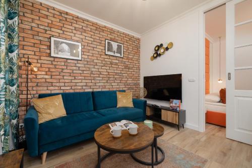 Beautiful & Stylish Apartaments Dietla with Air Conditioning by Renters في كراكوف: غرفة معيشة مع أريكة زرقاء وجدار من الطوب