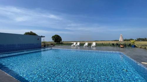 ein großer Pool mit Stühlen im Hof in der Unterkunft Country Road Homestay in Simpang Empat